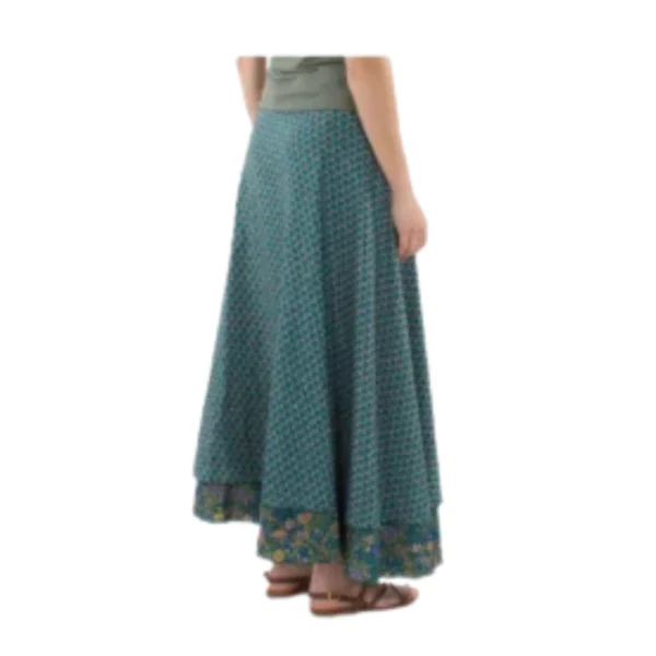 Une femme porte une jupe verte et bleue, mettant en valeur un style élégant et coloré.