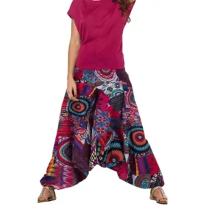 Une femme portant un pantalon harem à motifs colorés, se tenant debout avec un sourire joyeux.