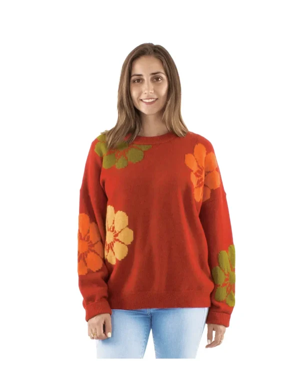 Femme portant un pull rouge orné de fleurs orange et vertes, affichant un style coloré et printanier.