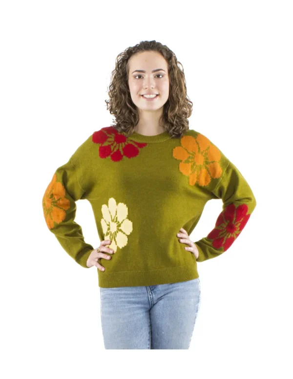 Femme portant un pull vert orné de fleurs multicolores, affichant un style vibrant et coloré.