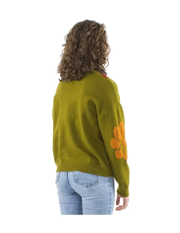 Femme portant un pull vert orné de fleurs multicolores, affichant un style vibrant et coloré.