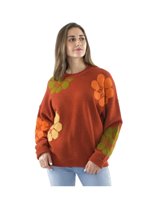 Femme portant un pull rouge orné de fleurs orange et vertes, affichant un style coloré et printanier.