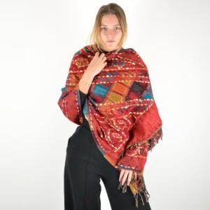 Femme portant un châle patchwork brodé multicolore rouge, or et bleu avec franges, style bohème chic