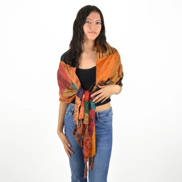 Femme portant une écharpe patchwork bohème en soie multicolore nouée sur un haut noir et un jean.
